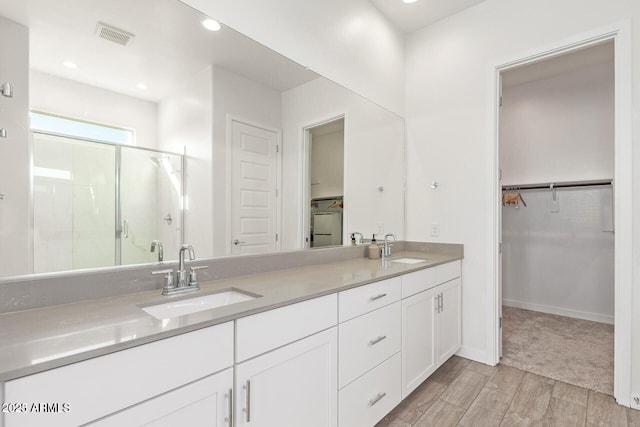 bathroom featuring double vanity, a shower stall, visible vents, and a sink