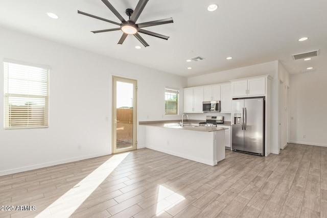 kitchen featuring stainless steel appliances, white cabinetry, visible vents, and light wood-style floors