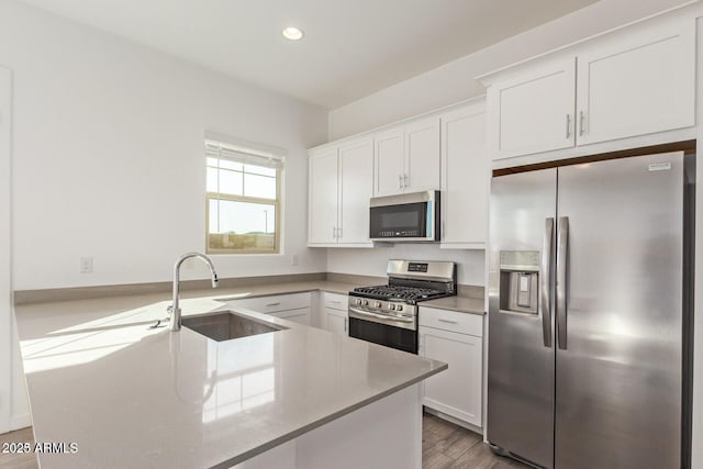 kitchen with light countertops, stainless steel appliances, white cabinetry, a sink, and recessed lighting