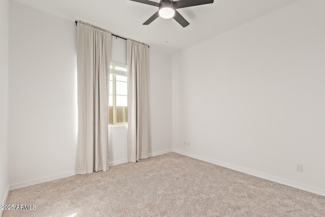 carpeted spare room featuring ceiling fan and baseboards