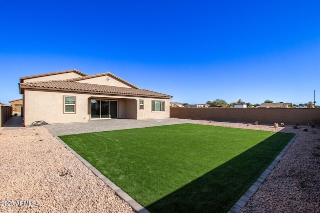 rear view of house with a patio, stucco siding, a lawn, a fenced backyard, and a tiled roof