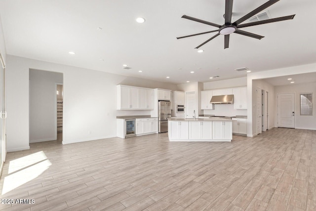 kitchen featuring open floor plan, high end fridge, a sink, and under cabinet range hood