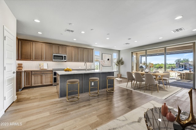 kitchen featuring light hardwood / wood-style flooring, sink, a breakfast bar, and a kitchen island with sink