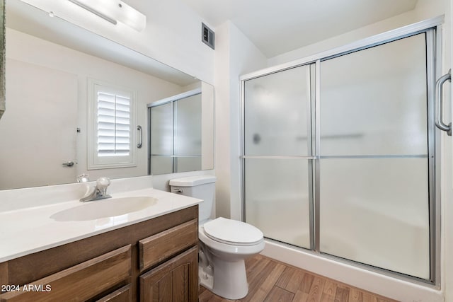 bathroom featuring toilet, hardwood / wood-style floors, walk in shower, and vanity