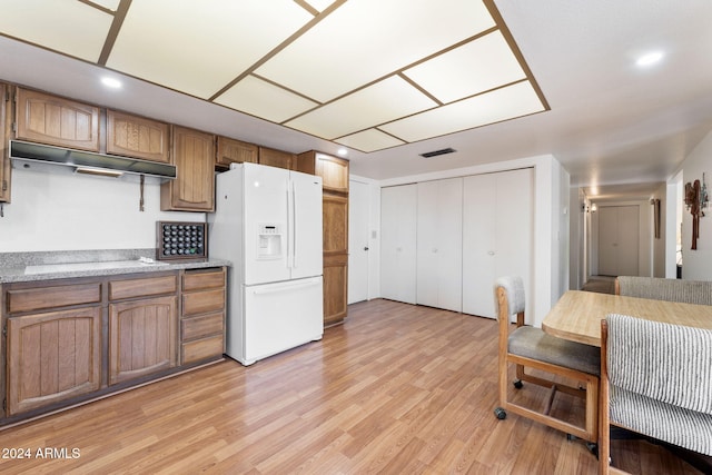 kitchen with black stovetop, light hardwood / wood-style floors, and white fridge with ice dispenser