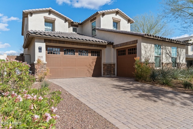 mediterranean / spanish house with a garage, stone siding, decorative driveway, and stucco siding