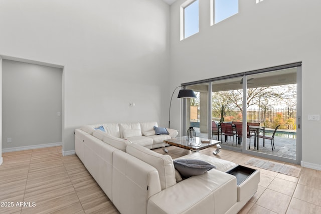 living room featuring a high ceiling, baseboards, and light tile patterned floors