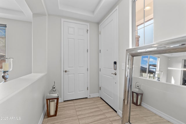 foyer featuring baseboards and a raised ceiling