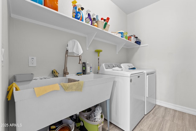 clothes washing area with laundry area, washing machine and dryer, and baseboards