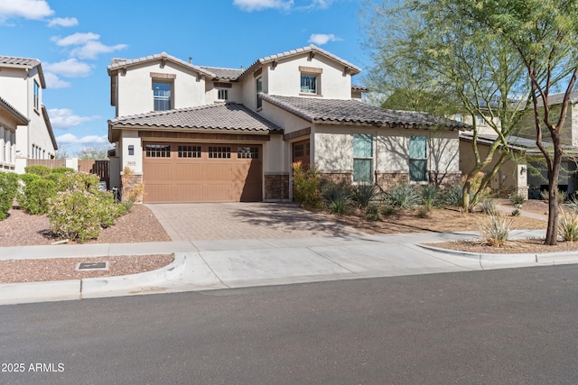 mediterranean / spanish-style house with stone siding, a tiled roof, fence, decorative driveway, and stucco siding