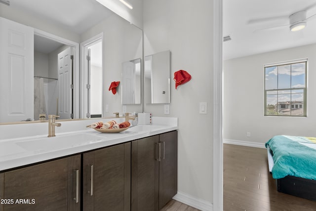 bathroom featuring double vanity, wood finished floors, a sink, and baseboards