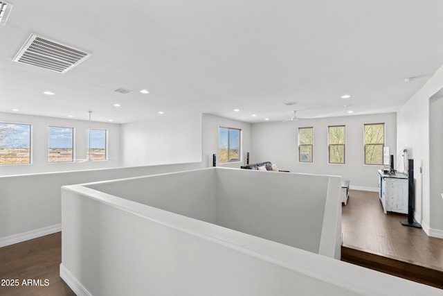 corridor with plenty of natural light, visible vents, dark wood finished floors, and an upstairs landing