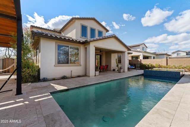 back of house with a fenced in pool, a tile roof, fence, a patio area, and stucco siding