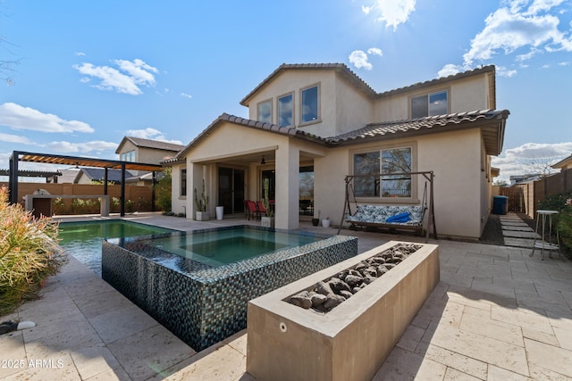 back of house with a fenced backyard, a tile roof, a pool with connected hot tub, stucco siding, and a patio area