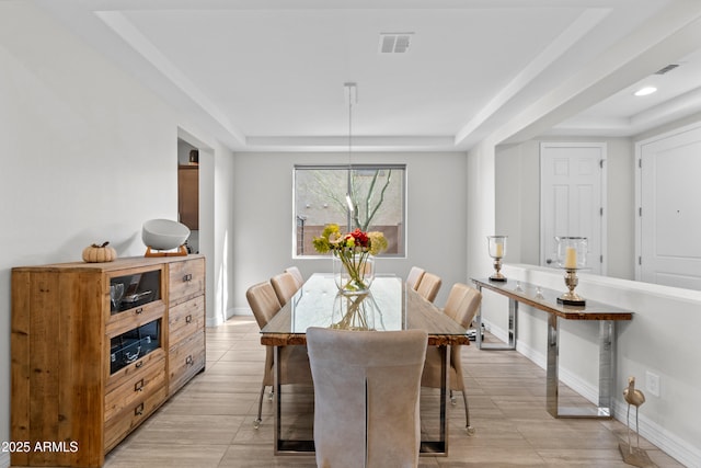 dining room featuring baseboards, visible vents, and a raised ceiling