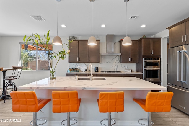 kitchen featuring wall chimney exhaust hood, visible vents, appliances with stainless steel finishes, and tasteful backsplash