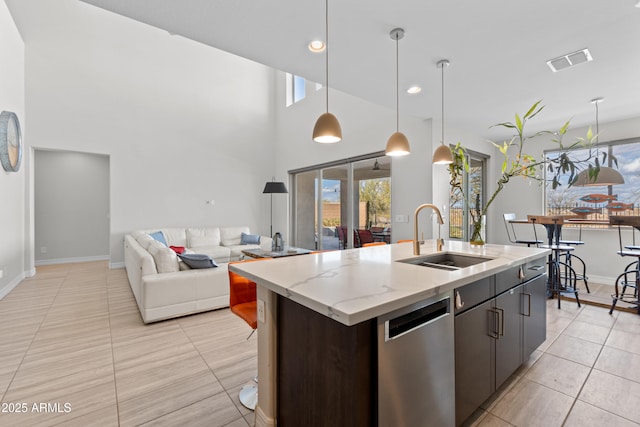 kitchen with a sink, visible vents, a healthy amount of sunlight, dishwasher, and a center island with sink