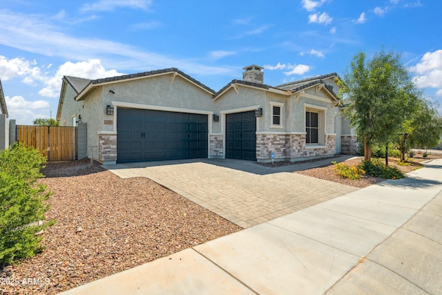 4619 N 179th Dr, Goodyear, AZ 85395 - view of front facade featuring an attached garage, stone siding, fence, stucco siding, and decorative driveway