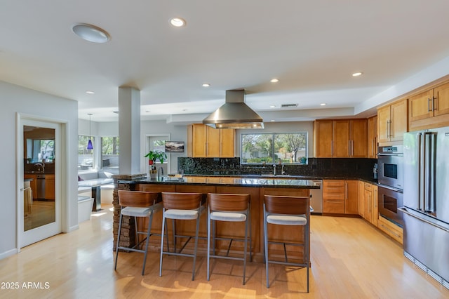 345 W Gardenia Dr, Phoenix, AZ 85021 - kitchen with island exhaust hood, backsplash, light wood-style floors, and appliances with stainless steel finishes
