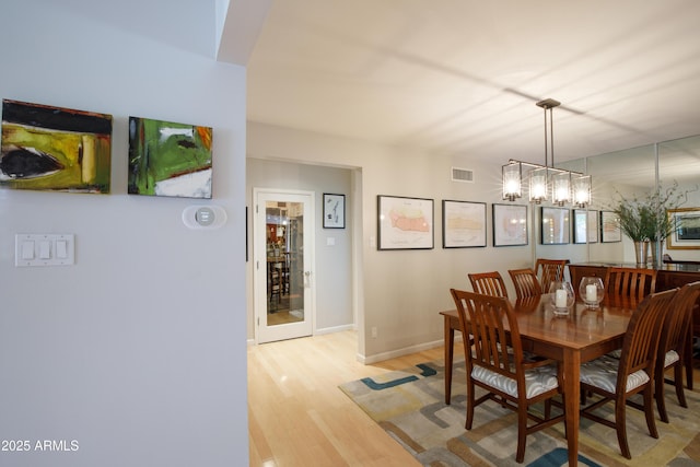 345 W Gardenia Dr, Phoenix, AZ 85021 - dining area featuring baseboards, light wood-type flooring, visible vents, and an inviting chandelier