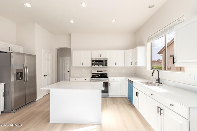 1112 E Winged Foot Dr, Chandler, AZ 85249 - kitchen with stainless steel appliances, a kitchen island, arched walkways, white cabinetry, and a sink