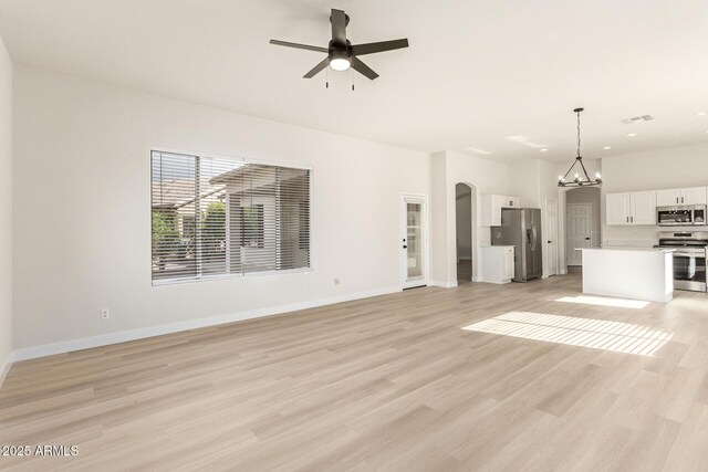 1112 E Winged Foot Dr, Chandler, AZ 85249 - unfurnished living room with light wood finished floors, baseboards, ceiling fan with notable chandelier, visible vents, and arched walkways