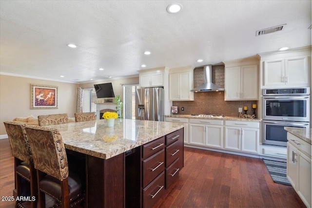 1670 E Whitten St, Chandler, AZ 85225 - kitchen with appliances with stainless steel finishes, wall chimney exhaust hood, dark wood-type flooring, a breakfast bar area, and crown molding