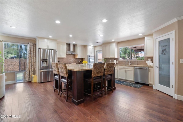 1670 E Whitten St, Chandler, AZ 85225 - kitchen featuring appliances with stainless steel finishes, wall chimney exhaust hood, ornamental molding, tasteful backsplash, and a center island