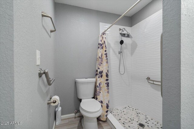 1670 E Whitten St, Chandler, AZ 85225 - bathroom with toilet, a tile shower, a textured wall, wood finished floors, and baseboards