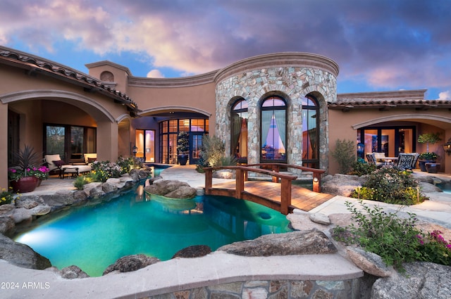 pool at dusk featuring french doors and an outdoor hangout area