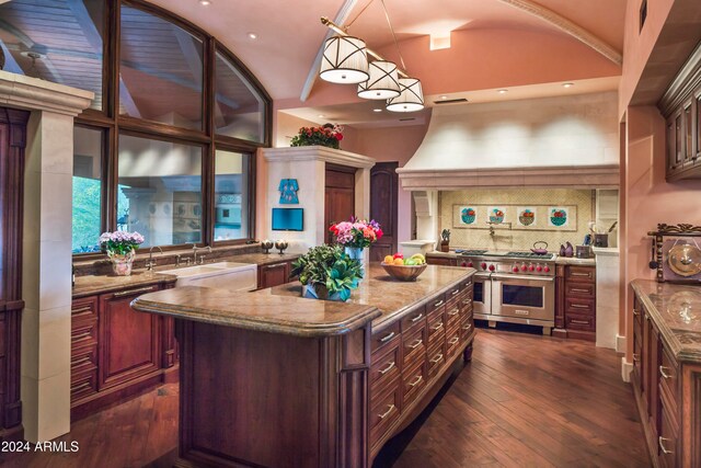 kitchen with decorative backsplash, sink, pendant lighting, range with two ovens, and a center island