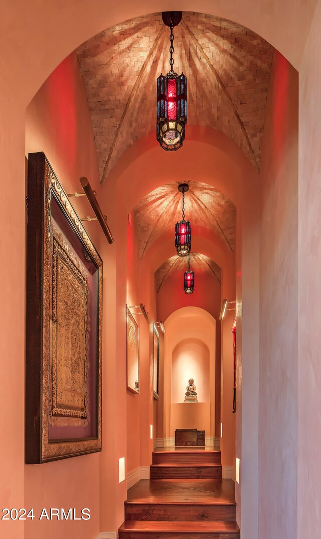 corridor with hardwood / wood-style floors, vaulted ceiling, and built in features