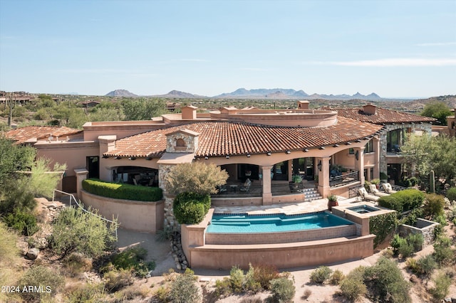 back of property with a mountain view, a pool with hot tub, and a patio area