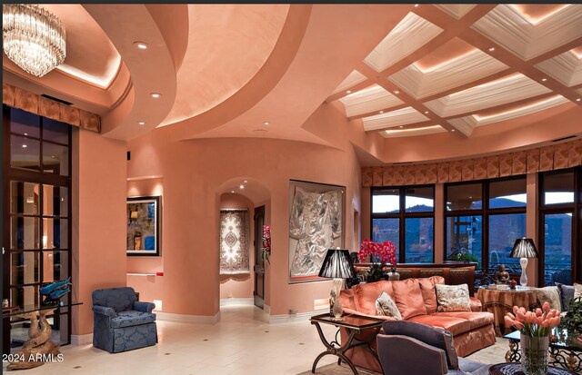 living room featuring a towering ceiling, coffered ceiling, light tile patterned floors, beamed ceiling, and a chandelier