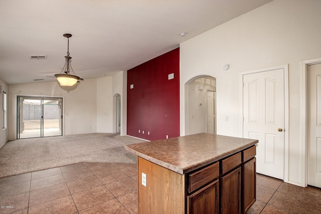 kitchen with a center island, light carpet, vaulted ceiling, ceiling fan, and decorative light fixtures