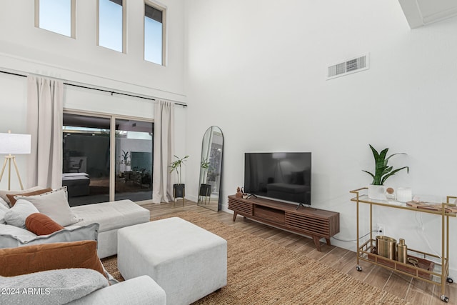 living room featuring a towering ceiling and light wood-type flooring