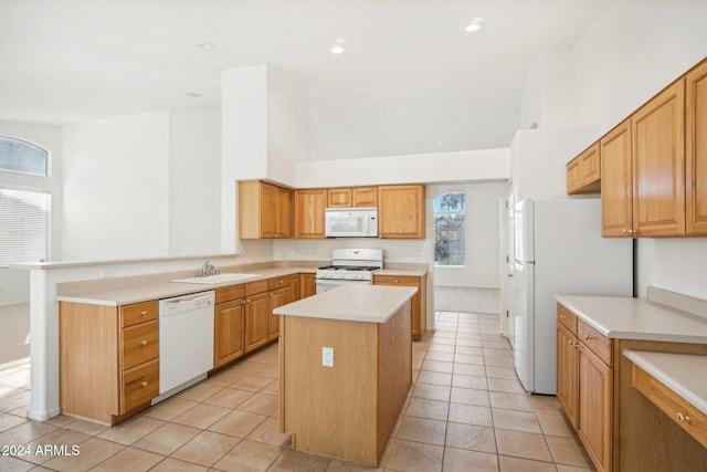 kitchen with sink, light tile patterned flooring, kitchen peninsula, white appliances, and a kitchen island