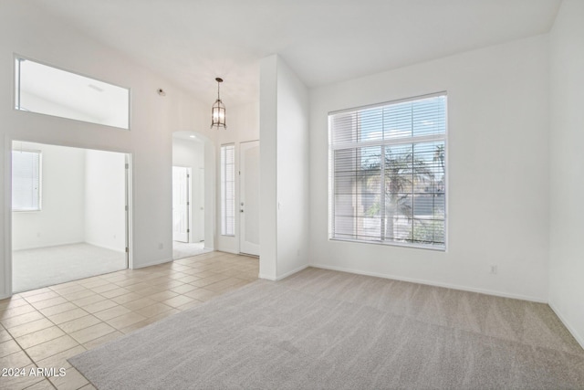 foyer entrance with light carpet, a chandelier, and vaulted ceiling