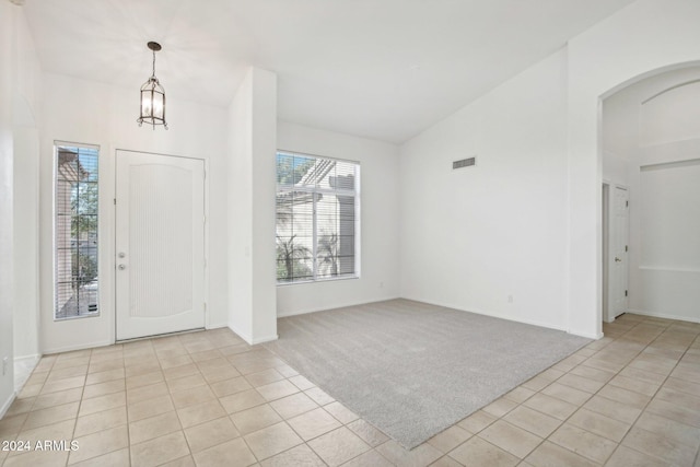 entryway with light carpet, vaulted ceiling, and a notable chandelier