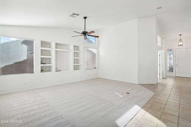 unfurnished living room with plenty of natural light, light tile patterned floors, and ceiling fan with notable chandelier