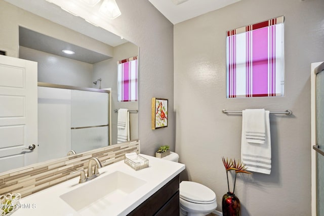 bathroom with decorative backsplash, an enclosed shower, vanity, and toilet