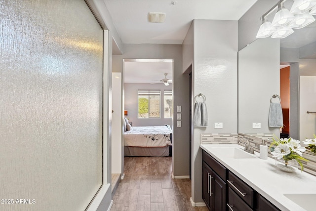 bathroom featuring a shower, hardwood / wood-style flooring, ceiling fan, decorative backsplash, and vanity