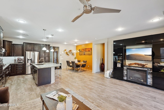 living room with ceiling fan, sink, and light hardwood / wood-style flooring