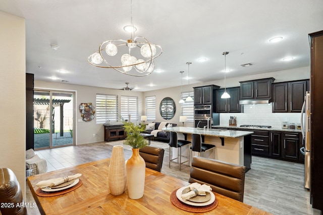 dining area featuring sink, ceiling fan with notable chandelier, and light hardwood / wood-style flooring