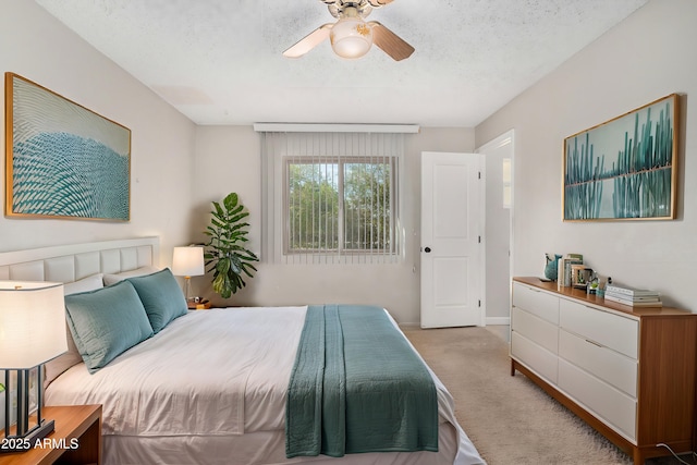 bedroom featuring ceiling fan, light carpet, and a textured ceiling