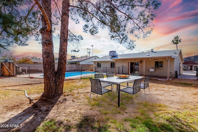 back house at dusk with a fenced in pool and a patio area