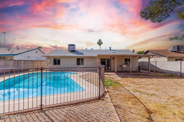 pool at dusk with a patio and central AC