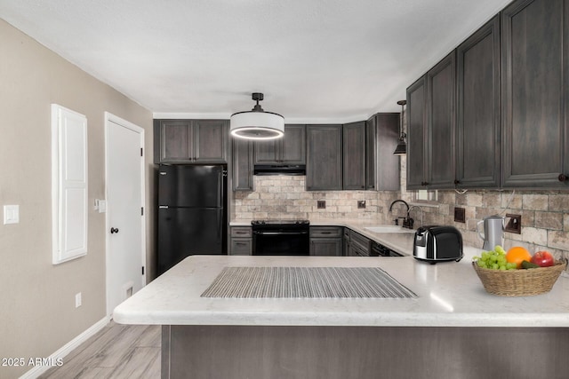 kitchen with black appliances, sink, backsplash, hanging light fixtures, and kitchen peninsula