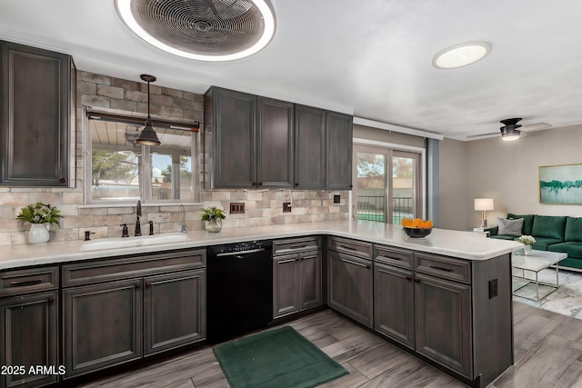 kitchen featuring pendant lighting, sink, black dishwasher, backsplash, and kitchen peninsula