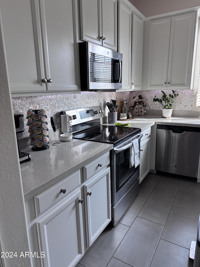 kitchen featuring backsplash, white cabinets, light stone countertops, light tile patterned flooring, and stainless steel appliances